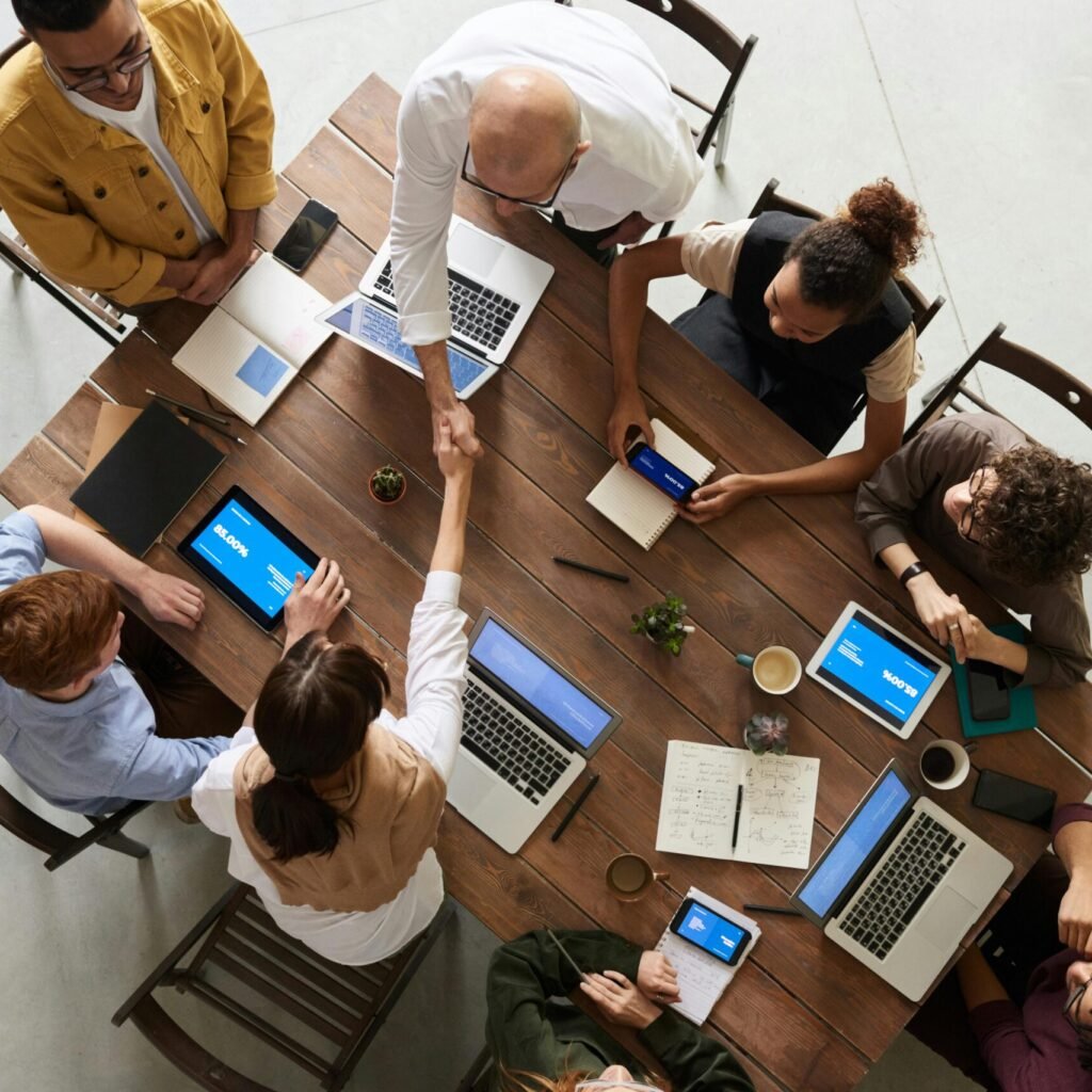 Top view of a diverse team collaborating in an office setting with laptops and tablets, promoting cooperation.